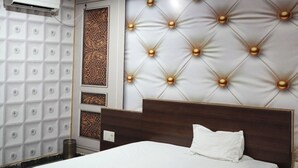 A bedroom with a large bed, a wall-mounted air conditioner, and a decorative headboard with light fixtures.
