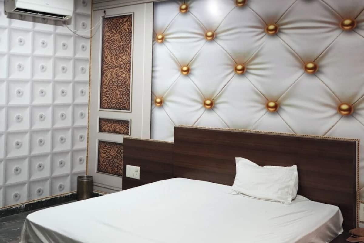Un dormitorio con una cama grande, aire acondicionado de pared y un cabecero decorativo con luces.