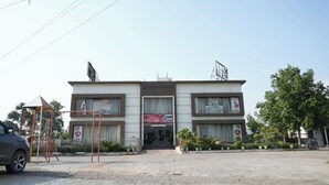 A two-story building with a sign for 'Haveli' and a 'Private Party' sign. There is a playground structure to the left and a tree to the right.