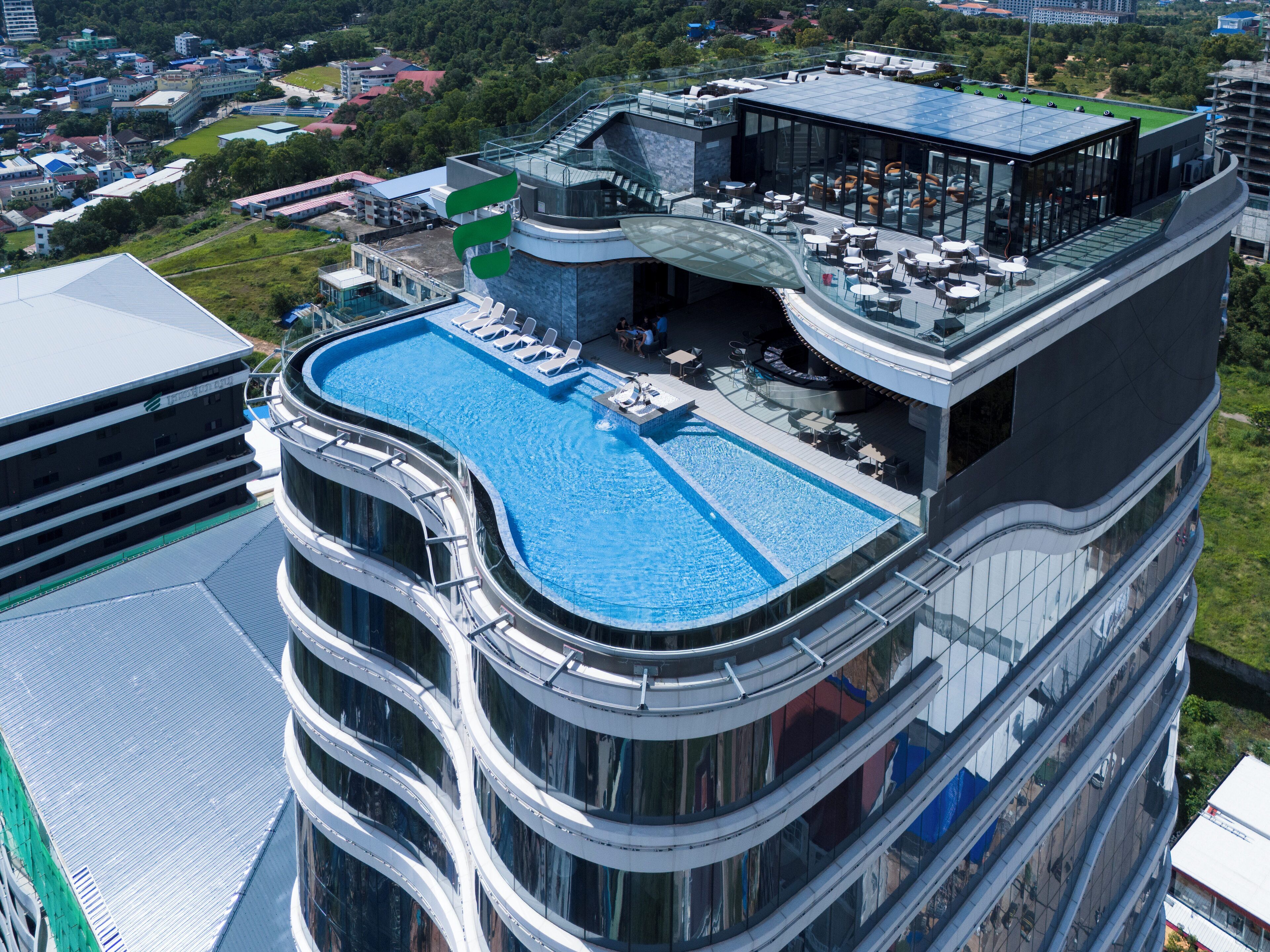 A high-rise building with a rooftop pool and outdoor seating area.