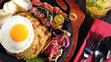 A plate of food with a fried egg, skewers, and a glass of drink.