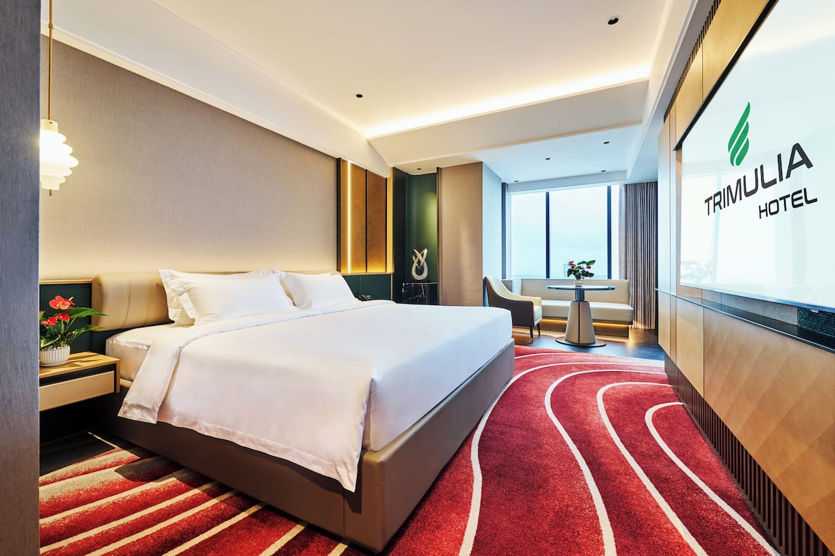A hotel room with a large bed, a desk, a chair, and a view of the city.