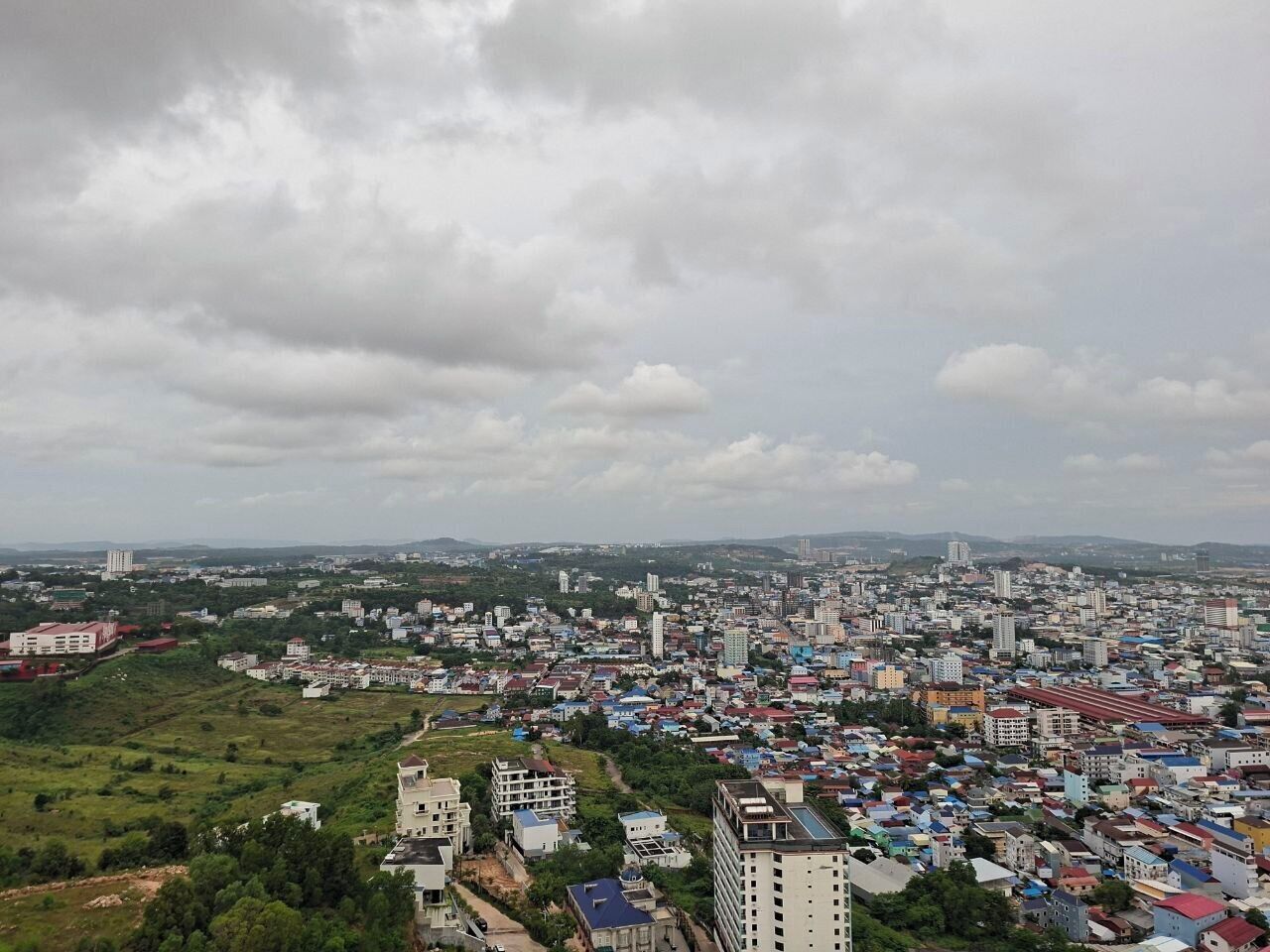 A cityscape with a mix of residential and commercial buildings, a prominent church, and a large open field in the foreground.