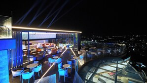 A rooftop bar with outdoor seating and a glass enclosure. - TRIMULIA Hotel (Sihanoukville)