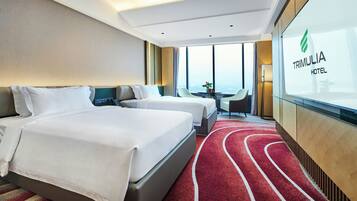 Ein Hotelzimmer mit zwei Betten, einem roten Teppich, Blick auf die Stadt und einer Glaswand mit dem Hotelnamen.