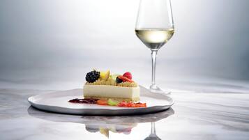 Un postre en un plato, con una copa de vino blanco a su lado.