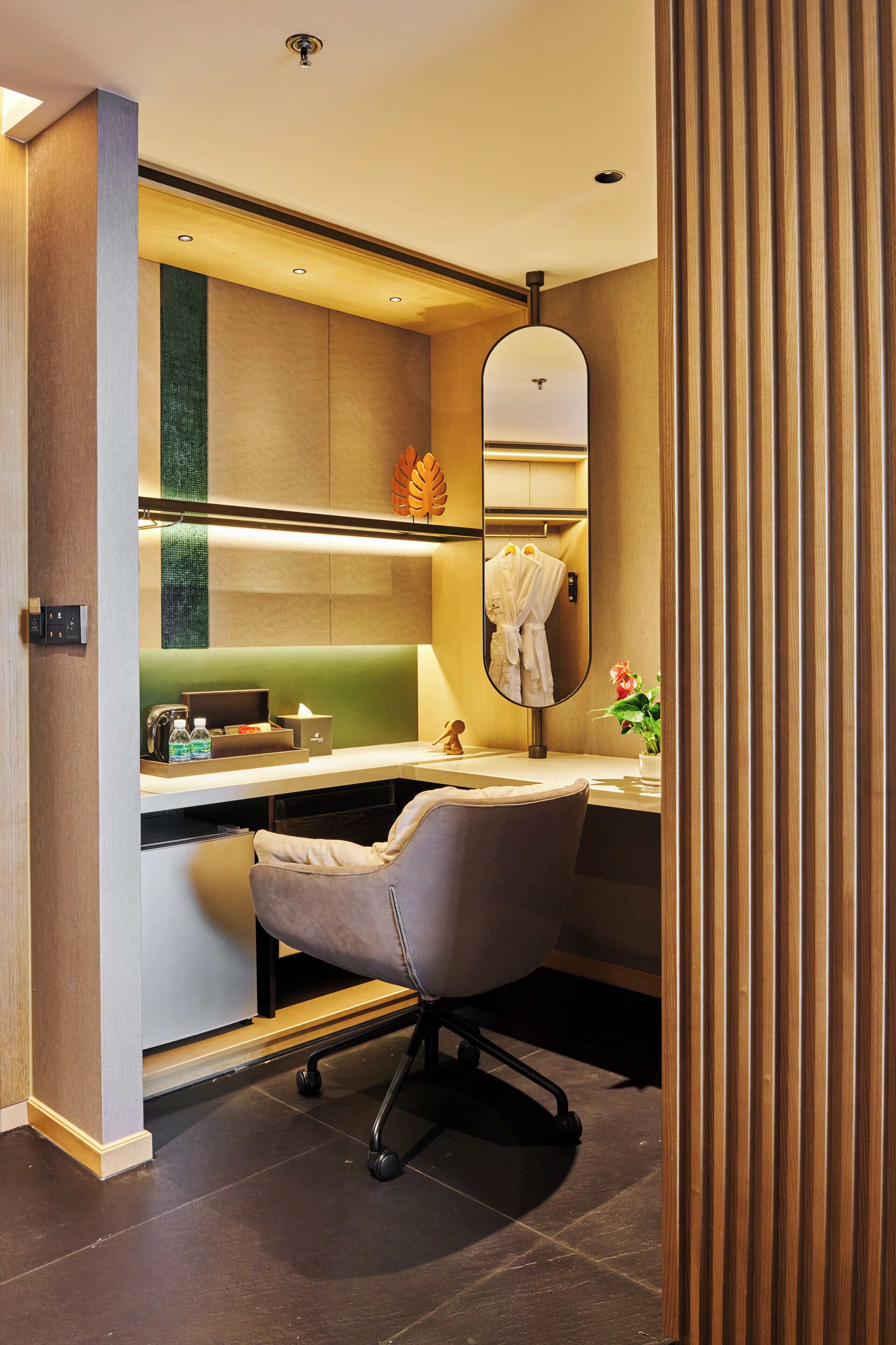 A modern bathroom with a vanity, mirror, and seating area.