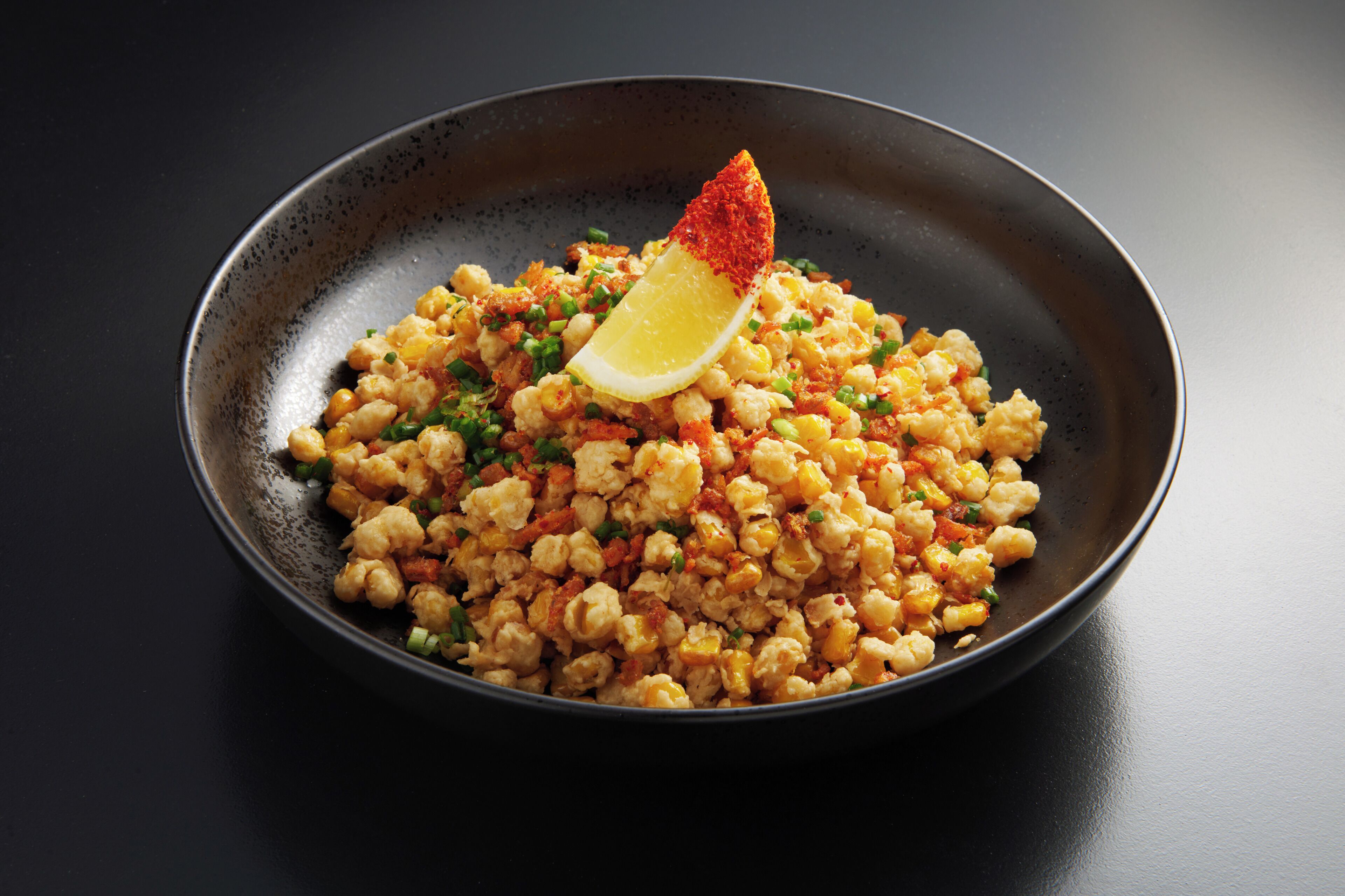 A bowl of food with a lemon wedge on top.