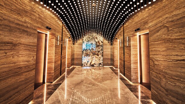 A modern elevator interior with a polished marble floor and wooden walls, featuring a unique ceiling design with circular lights. - TRIMULIA Hotel (Sihanoukville)