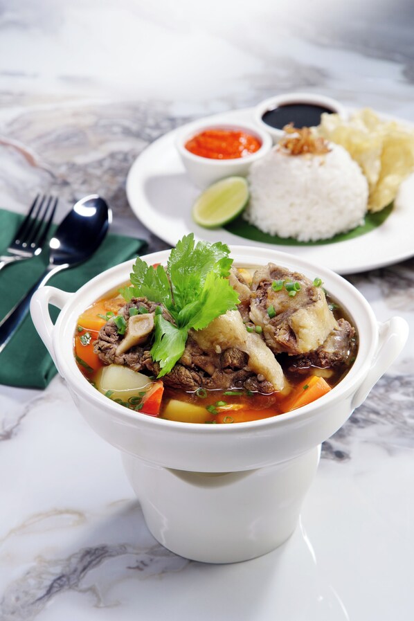 A bowl of soup with meat and vegetables, a plate of rice, and a small bowl of sauce. - TRIMULIA Hotel (Sihanoukville)