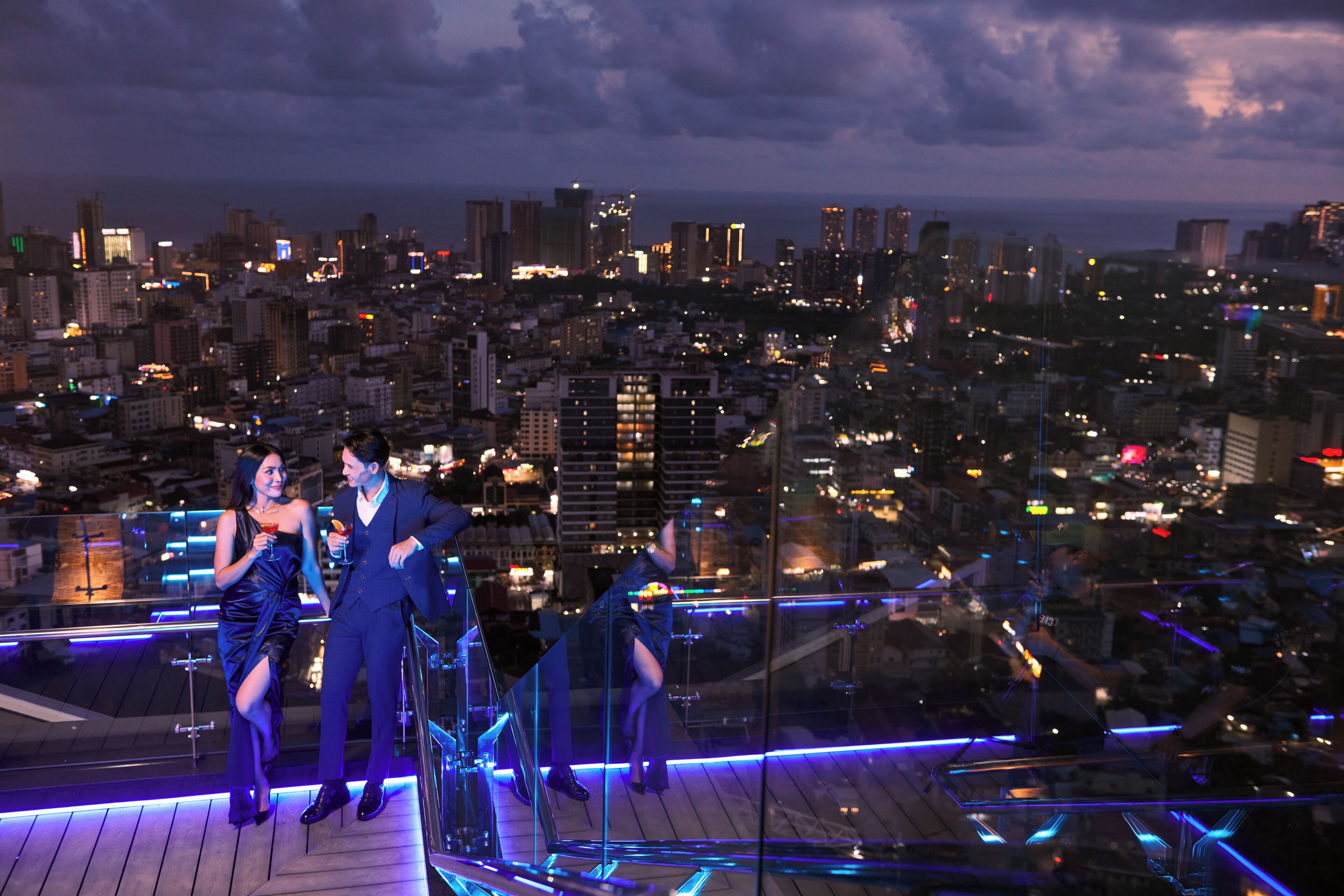 A couple on a balcony with a cityscape view.