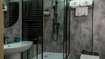 A modern bathroom with a glass-enclosed shower, a sink, and a toilet.