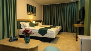 A hotel room with a bed, bedside table, a vase with flowers, a desk, a chair, and a television. - MSInternational Hotel (Ulaanbaatar)