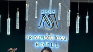 A reception desk at MS International Hotel with a marble top, a potted plant, and hanging crystal-like light fixtures. - MSInternational Hotel (Ulaanbaatar)