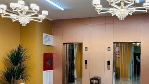 A modern lobby with marble flooring, a potted plant, a trash bin, and two elevators. - MSInternational Hotel (Ulaanbaatar)