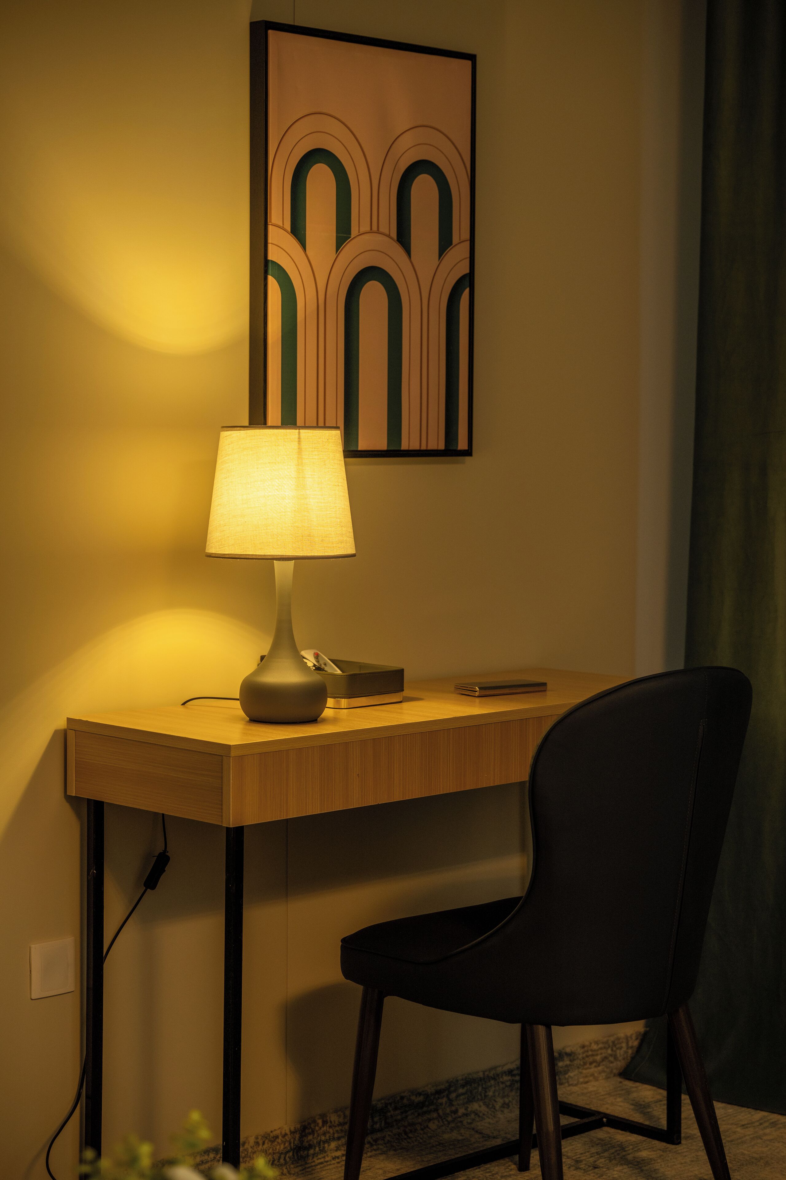 Un escritorio con una lámpara, una silla y un cuadro en la pared.