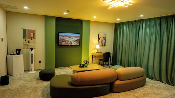 A modern living room with a flat-screen TV, a coffee machine, a small table, and a sofa. - MSInternational Hotel (Ulaanbaatar)