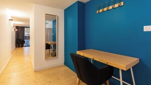 Une pièce avec un plancher en bois, une chaise noire, une table en bois, un mur bleu et un miroir.