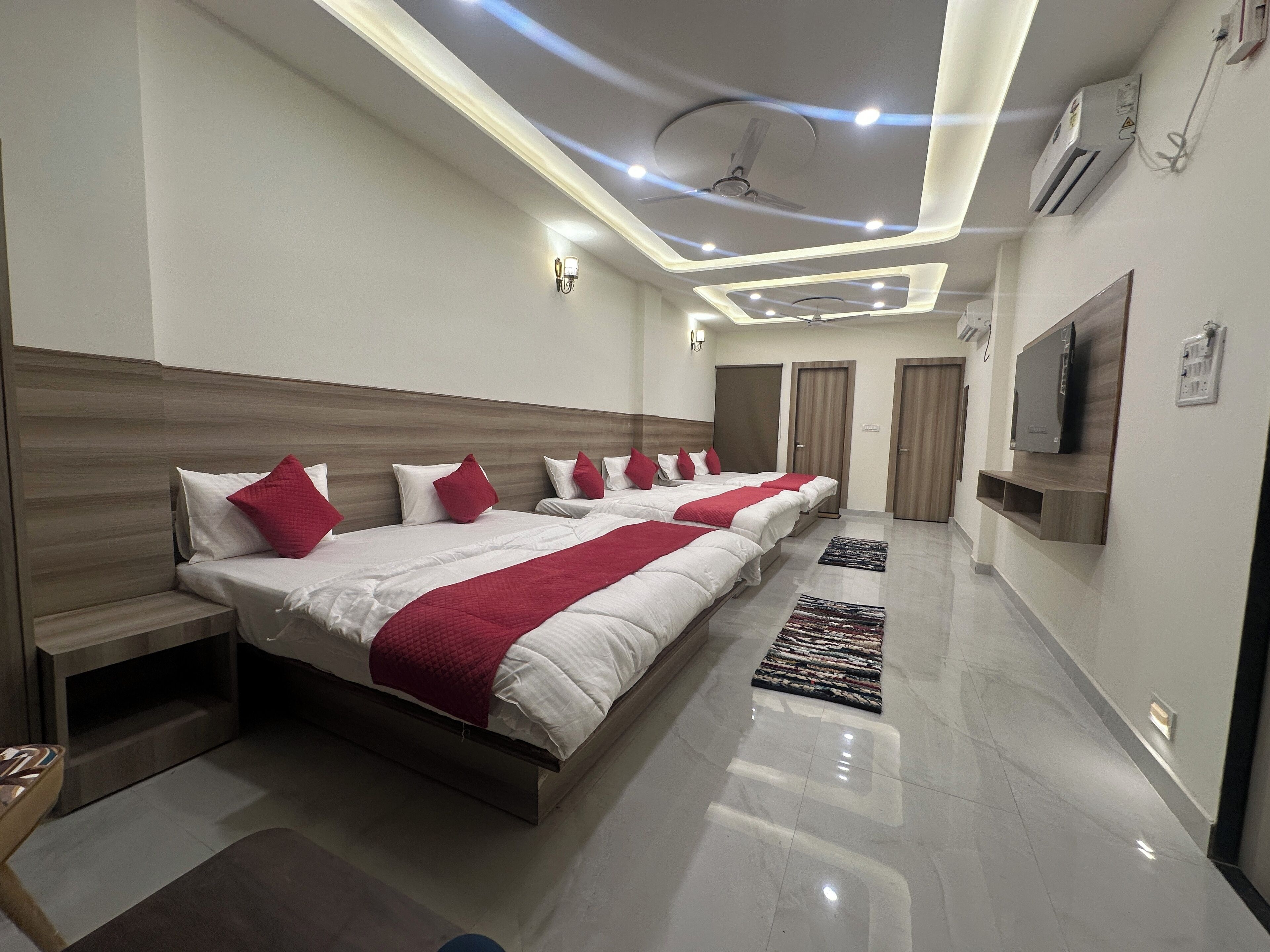 Habitación de hotel moderna con una cama grande, ventilador de techo, iluminación empotrada y un televisor de pantalla plana montado en la pared.