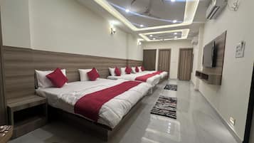 Habitación de hotel moderna con una cama grande, ventilador de techo, iluminación empotrada y un televisor de pantalla plana montado en la pared.
