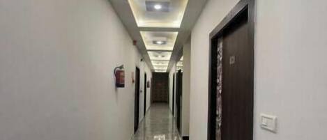 A hallway with a marble floor, recessed lighting, and a blue mat at the entrance.