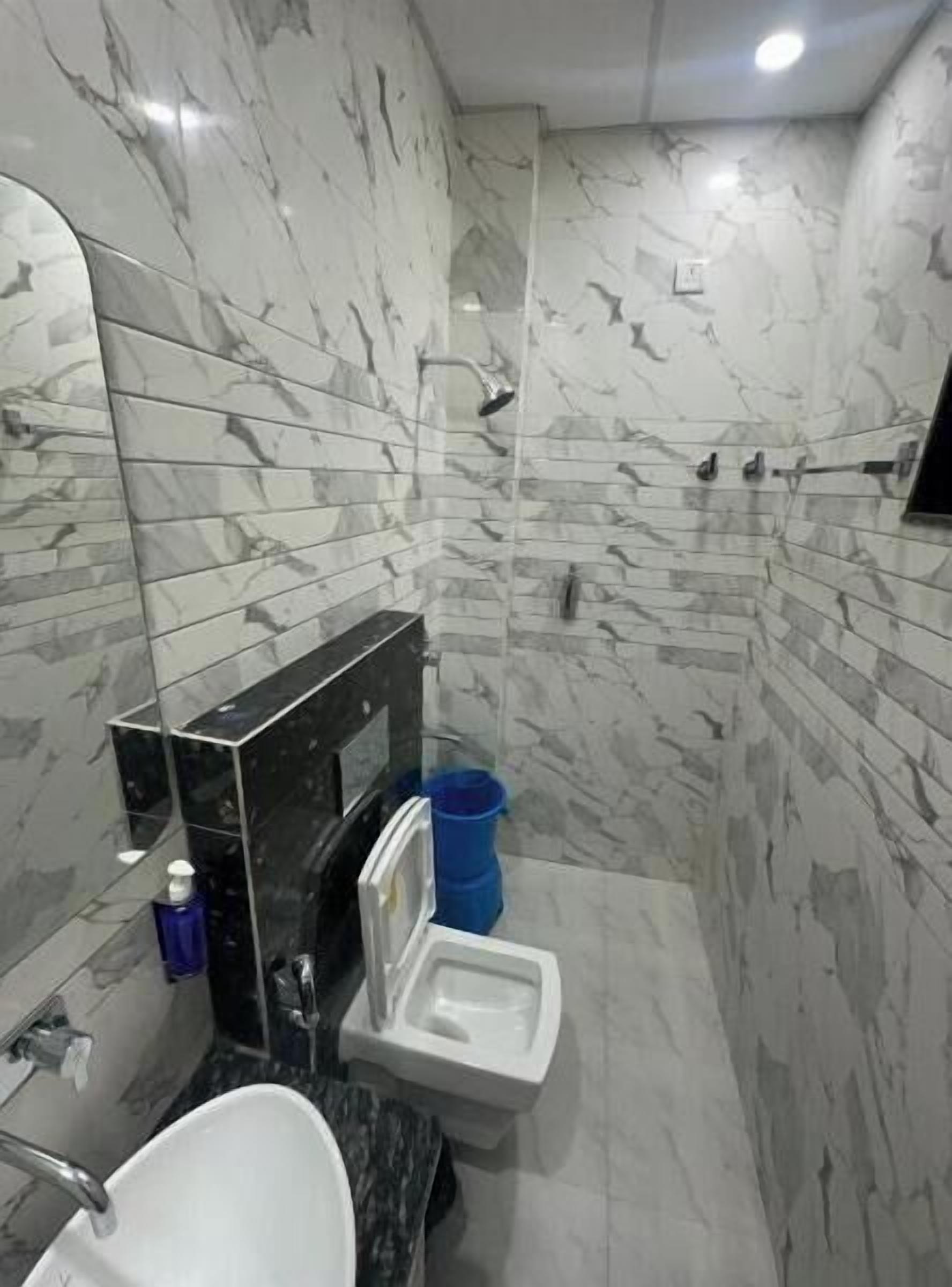 Un baño con paredes de mármol, un lavabo, un inodoro y una ducha.