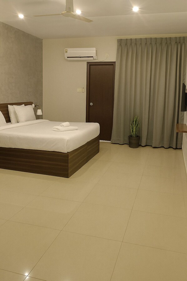 A modern bedroom with a large bed, an air conditioning unit, a ceiling fan, a door, and a potted plant.