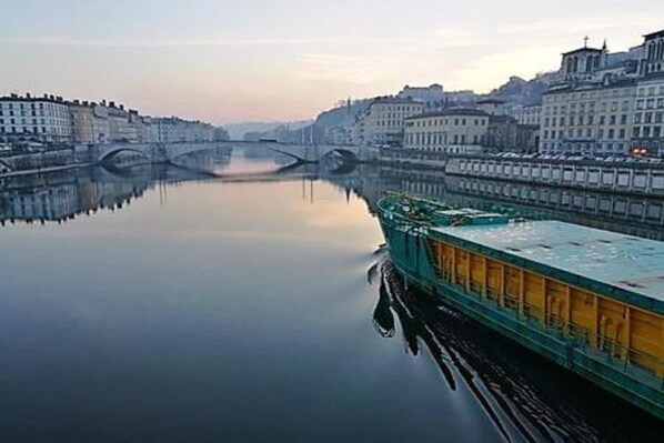 Une rivière paisible, avec un pont et des bâtiments qui bordent ses rives.