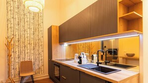 Une cuisine moderne avec un plan de travail en bois, des armoires noires, un lave-vaisselle encastré et un luminaire suspendu.