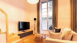 Un salon avec un téléviseur, un canapé, une table basse et un escalier.