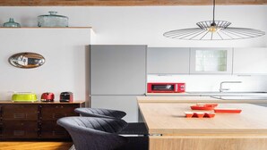 A modern kitchen with a wooden island, a red microwave, and a unique pendant light. - DIFY Roi Lyon - Hotel de Ville (Lyon)
