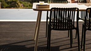A table with chairs and a book on a balcony overlooking a body of water and buildings.