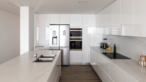 A modern kitchen with white cabinetry, stainless steel appliances, and a marble countertop.