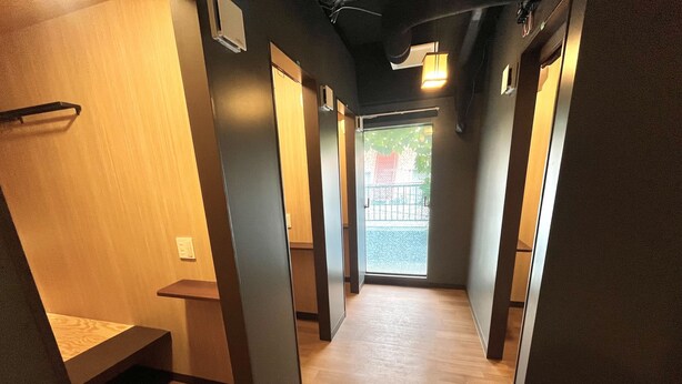 Un pasillo con piso de madera, un banco y una puerta que da a un balcón.