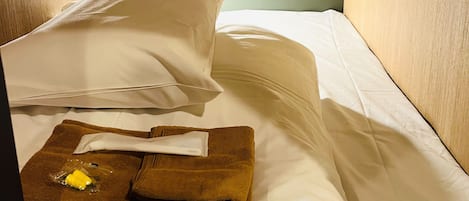 A small, single-bed room with a wooden headboard, a bedside table, and a nightstand.