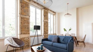 Ein modernes Wohnzimmer mit einem blauen Sofa, einem Korbstuhl und einem Holztisch.