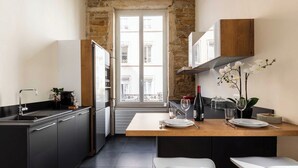 Eine moderne Küche mit einer zentralen Kochinsel, schwarzen Schränken und Blick auf die Stadt durch ein großes Fenster.
