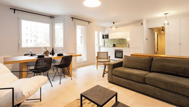 A modern apartment with a dining area, kitchen, and living room.