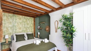 A bedroom with a bed, green walls, wooden beams, a potted plant, and a white wardrobe. - DIFY Boileau - Quartier Foch (Lyon)