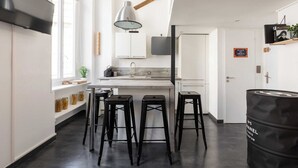 A modern kitchen with a large window, a hanging light fixture, and a bar area with stools. - DIFY Boileau - Quartier Foch (Lyon)