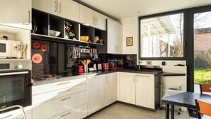 A modern kitchen with a black refrigerator, white cabinets, and a large window. - DIFY Stoppa - Parilly (Vénissieux)