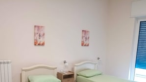 Une chambre avec deux lits, un radiateur et des œuvres d’art accrochées aux murs.