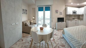 Une chambre moderne comprenant un lit, une table à manger avec des chaises, un canapé, un téléviseur et un coin cuisine.
