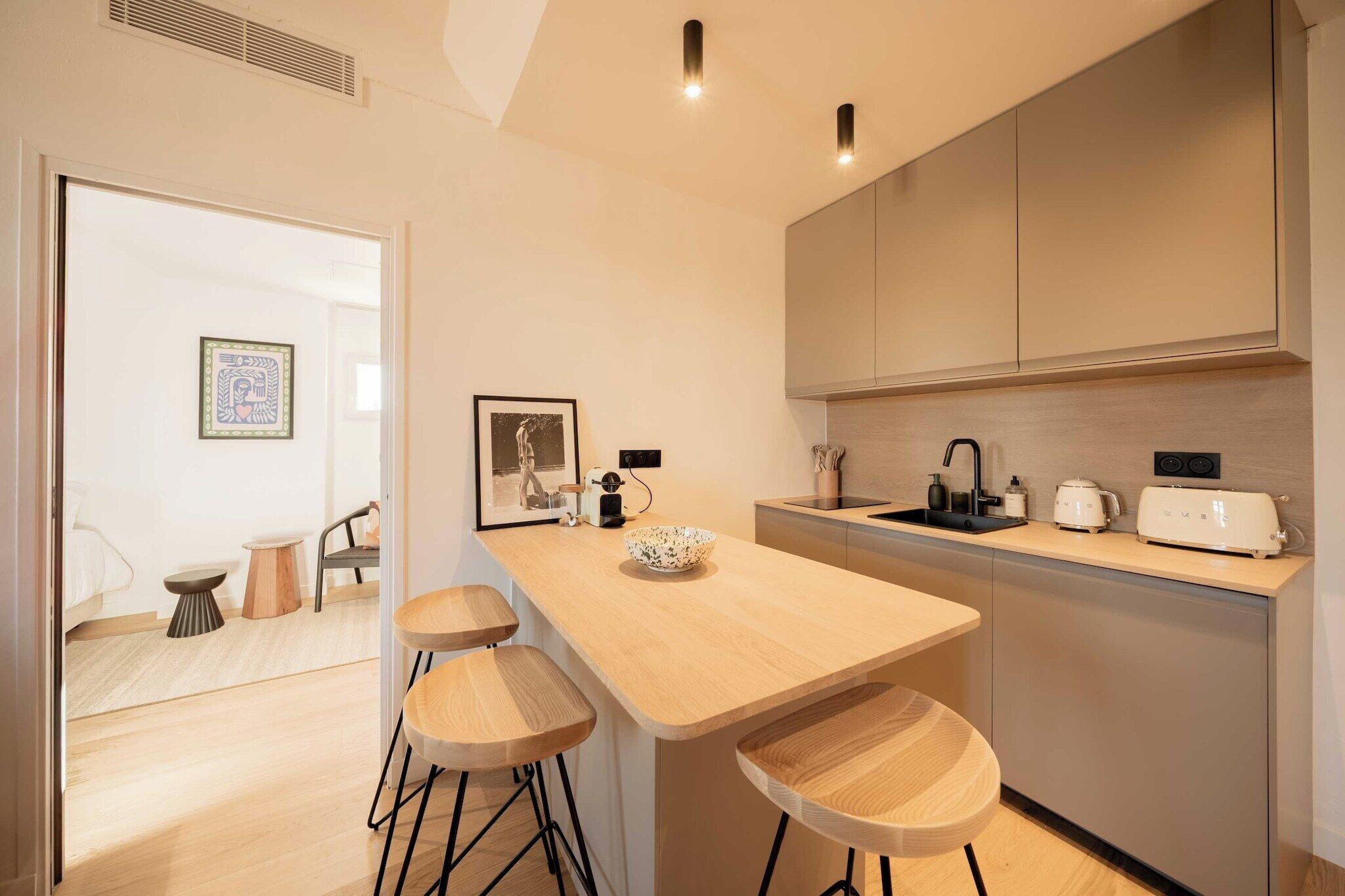 A modern kitchen with a wooden countertop, bar stools, a sink, and a toaster.
