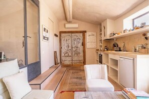 A compact living space with a kitchenette, a sofa, a dining table, and a sliding door leading to another room.