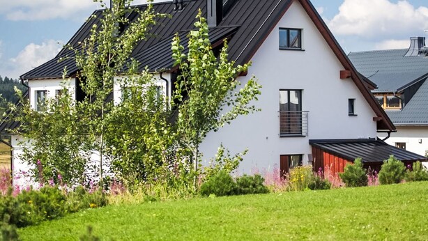 A two-story house with a sloped roof, white exterior walls, and a chimney. - Apartment BD-D by Interhome (Bozi Dar)