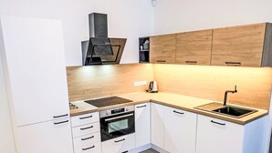 A modern kitchen with white cabinets, wooden countertops, a built-in oven, a stove, and a sink. - Apartment BD-D by Interhome (Bozi Dar)