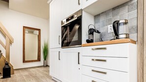 A modern kitchen with white cabinetry, a wooden countertop, and a built-in oven. - Apartment Ness by Interhome (Bozi Dar)
