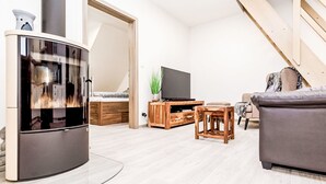 A modern living room with a curved TV, wooden furniture, a sofa, and a staircase. - Apartment Ness by Interhome (Bozi Dar)