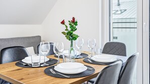 Ruokapöytä on katettu lautasilla, laseilla ja maljakolla, jossa on kukkia.